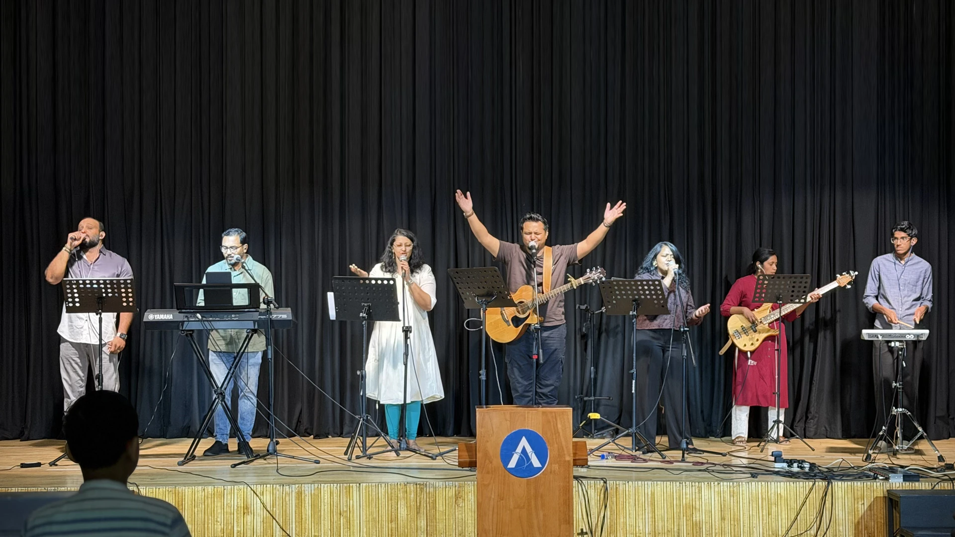 A musician from the ALF Kuwait worship band playing bass guitar during a service.